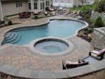 Patio surrounding bi-level poolscape with upper-level spa and back retaining wall